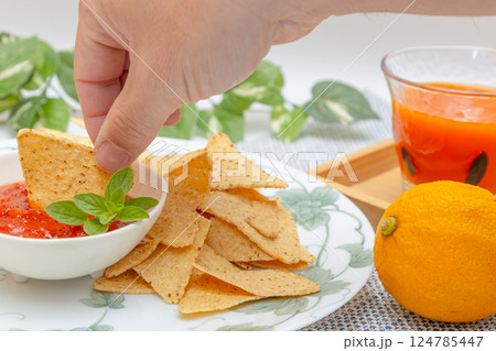 トウモロコシからできているトルティーヤチップスとサルサソースと野菜ジュース 124785447