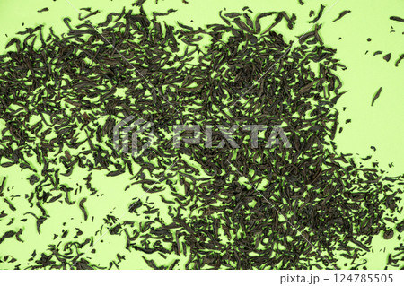 Scattered leaves of black large leaf tea on green background top view 124785505