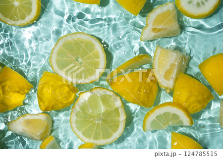 Refreshing turquoise citrus background with floating yellow lemon pieces 124785515
