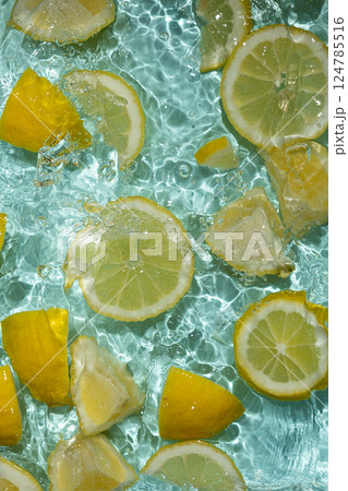 Refreshing turquoise citrus background with floating yellow lemon pieces Refreshing turquoise citrus background with floating yellow lemon pieces 124785516