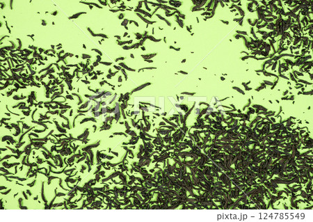 Scattered leaves of black large leaf tea on green background top view 124785549