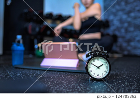 ジムで運動する時間　時計　タブレットでYouTube動画を見ながらジムで運動する女性　 124785862