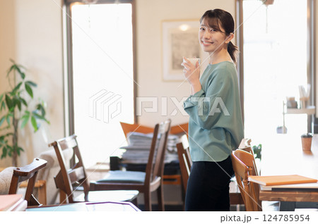 立ってコーヒーを飲みながらリラックスする女性 124785954