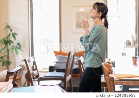 立ってコーヒーを飲みながらリラックスする女性 124785955