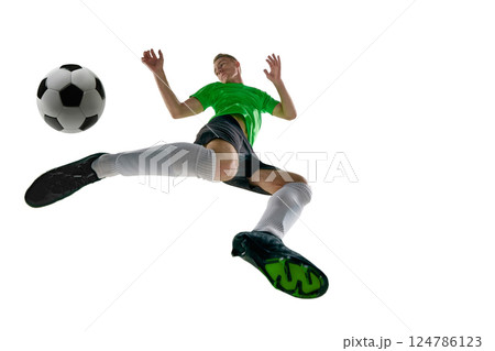 Low angle of athletic man, dressed sport uniform, soccer player raising foot for stop ball in motion against white studio background. Low angle of athletic man, dressed sport uniform, soccer player raising foot for stop ball in motion against white studio background. 124786123