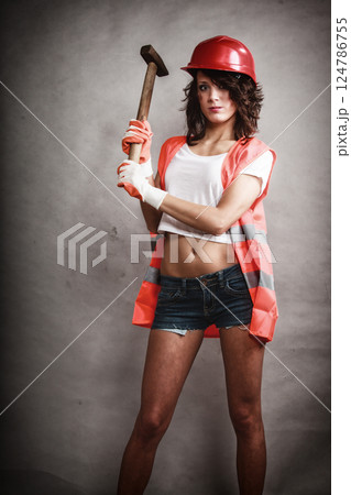 Sexy girl in safety helmet holding hammer tool Sexy girl in safety helmet holding hammer tool 124786755