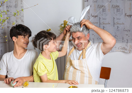 Happy father having fun with his kids while wearing bunny ears headband. Joyful Easter moments, spring family celebration, playful bonding time at home. Happy father having fun with his kids while wearing bunny ears headband. Joyful Easter moments, spring family celebration, playful bonding time at home. 124786873