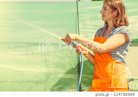 Woman watering the garden with hose Woman watering the garden with hose 124786989