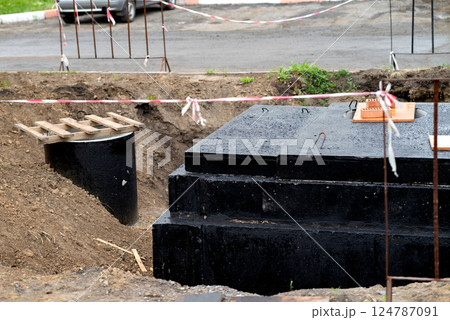 Construction site showing excavation for foundation work in a residential area with safety barriers and machinery nearby 124787091