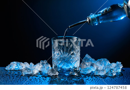 Vodka pours from bottle to glass. Vodka pours from bottle to glass. 124787458