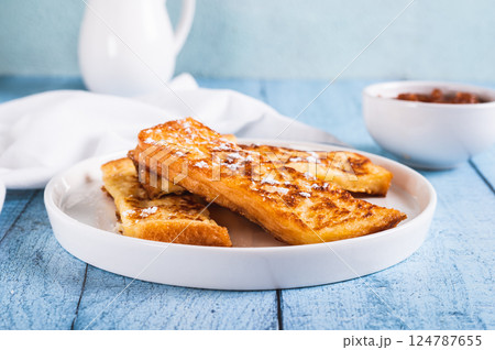 Appetizing croutons in powdered sugar on a plate on the table 124787655