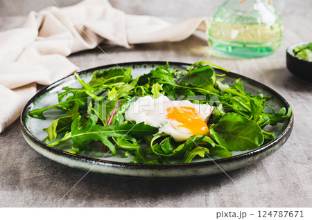 Poached egg in arugula and chard leaves on a plate on a table Poached egg in arugula and chard leaves on a plate on a table 124787671