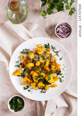 Baked spicy cauliflower with onions and parsley on a plate on the table top and vertical view 124787688