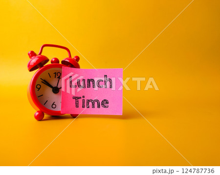 Red alarm clock with sticky note with the word Lunch Time on a yellow background. 124787736