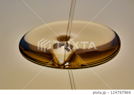 Texture of pouring cosmetic oil on a golden background. 124787969
