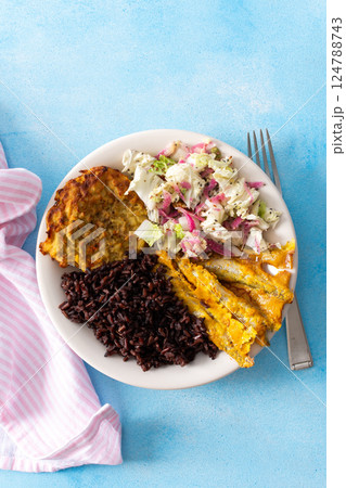 A wholesome and savory breakfast with brown rice and baked white fish, complemented by zucchini-carrot pancakes and a fresh Chinese cabbage salad with radish 124788743