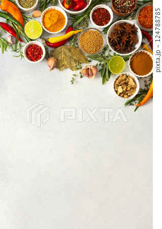 Colorful herbs and spices scattered across a gray surface, ideal for creating authentic and flavorful dishes, top view and copy space 124788785