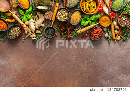 A vibrant collection of fresh, fragrant spices and herbs arranged in a colorful display on a rich brown backdrop, showcasing their natural and aromatic beauty 124788793