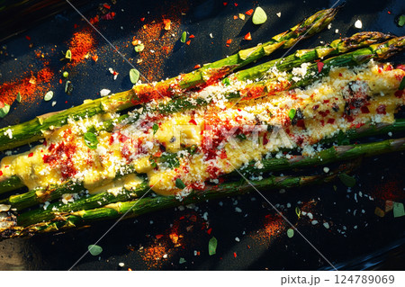 Fresh asparagus grilled to perfection, sprinkled with chili flakes and Parmesan cheese, served on a plate. A crunchy, healthy, and flavorful side dish, ideal for any meal or light lunch 124789069