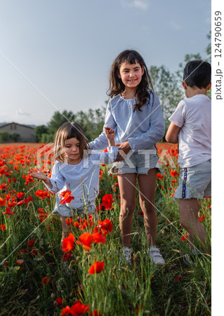 three children playing in a poppy field 124790659