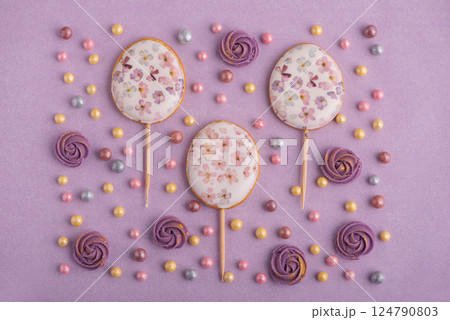 Easter decor for cake: easter eggs, colorful sugar sparkles and flowers on pastel puple background. Top view Easter decor for cake: easter eggs, colorful sugar sparkles and flowers on pastel puple background. Top view 124790803