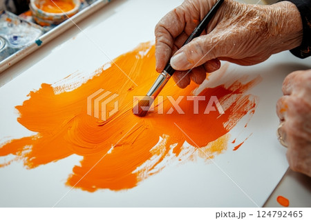 Creative expression through painting with vibrant orange hues on canvas at an art studio 124792465