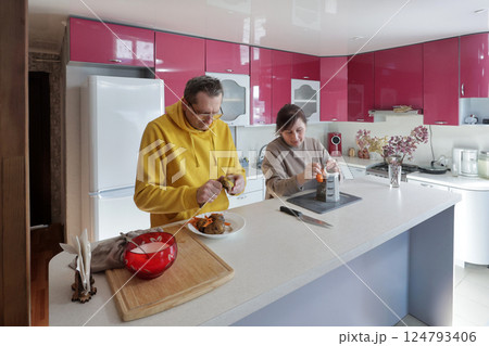Man and woman stand side by side in kitchen as they prepare vegetables together each focused on their task while enjoying quiet shared moment at home. Man and woman stand side by side in kitchen as they prepare vegetables together each focused on their task while enjoying quiet shared moment at home. 124793406
