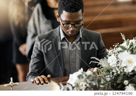 Funeral coffin, death and black man sad, grieving and mourning loss of family, friends or dead loved one. Church service, floral flowers and person with casket, grief and sadness over loss of life Funeral coffin, death and black man sad, grieving and mourning loss of family, friends or dead loved one. Church service, floral flowers and person with casket, grief and sadness over loss of life 124794190