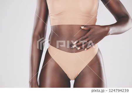 Hand, stomach and body with a model black woman touching her tummy in studio on a gray background for wellness. Health, underwear and diet with a female posing for healthy eating or lifestyle Hand, stomach and body with a model black woman touching her tummy in studio on a gray background for wellness. Health, underwear and diet with a female posing for healthy eating or lifestyle 124794239
