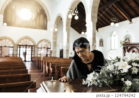 Widow, coffin and sad at a funeral feeling depression from death sitting in a church. Depressed Indian woman with mourning, grief and mental health problem at an emotional religion burial event 124794242