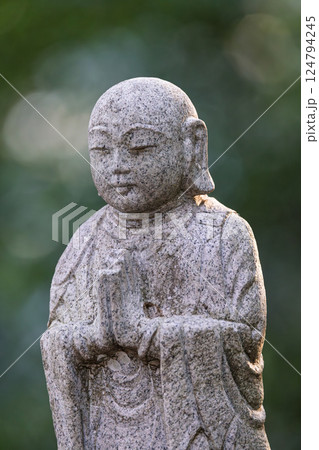 微笑みを浮かべ手を合わせる仏の石像 124794245