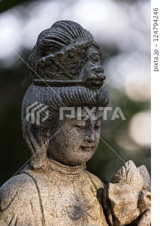 微笑みを浮かべ手を合わせる仏の石像 124794246
