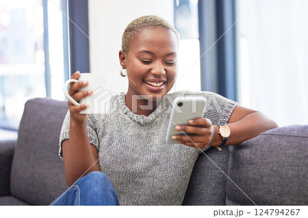 Woman, phone and relax on sofa with coffee for morning routine scroll social media. Happy African girl, streaming on smartphone and read digital 5g communication on couch with tea in living room 124794267