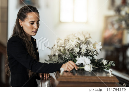 Funeral, sad and woman with flower on coffin after loss of a loved one, family or friend. Grief, death and young female putting a rose on casket in church with sadness, depression and mourning Funeral, sad and woman with flower on coffin after loss of a loved one, family or friend. Grief, death and young female putting a rose on casket in church with sadness, depression and mourning 124794379