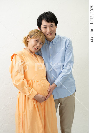 妊娠中の妻のお腹に手をあてて寄り添う夫 124794570