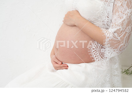 座ってお腹に手を当てる妊婦 124794582