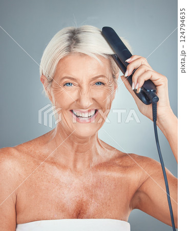 Portrait of an old woman in studio with a hair iron for grooming, hair care treatment and salon hairstyle. Beauty, self care and happy elderly person hairdressing with a hair straightener for shine 124794635