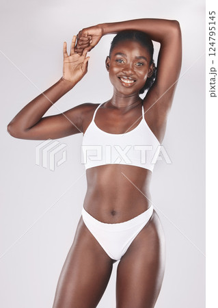 Health, body and portrait of a black woman in a studio for fitness, exercise and wellness. Body care, beauty and healthy African model with a smile isolated posing by a gray background for self love. Health, body and portrait of a black woman in a studio for fitness, exercise and wellness. Body care, beauty and healthy African model with a smile isolated posing by a gray background for self love. 124795145