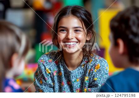 Young girl with a joyful expression surrounded by two kids in a colorful room setting. Concept of happiness and youthful interaction. For a family-oriented lifestyle article. 124795198