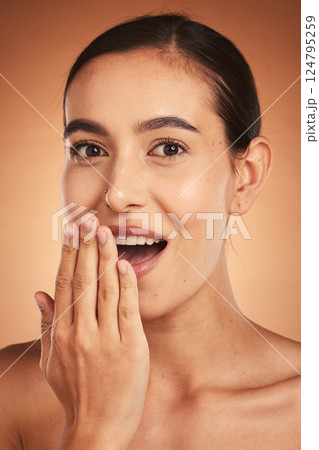 Wow, gossip, and woman with hand for beauty, makeup and cosmetics against a brown studio background. Skincare, happy and young model with surprise from cosmetic care, cosmetology and dermatology 124795259