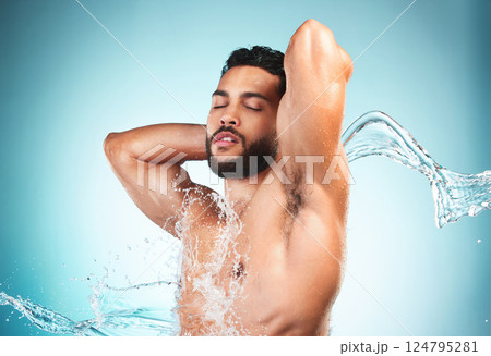 Beauty, shower and water with a man model in studio on a blue background for hygiene or hydration. Wellness, cleaning and splash with a handsome young male washing or cleansing in the bathroom alone 124795281