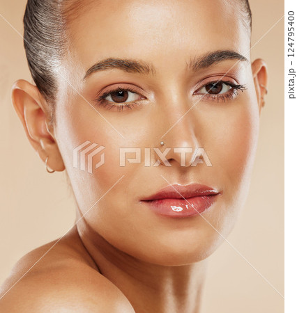 Face, beauty and skincare with a model woman in studio on a beige background for natural care or treatment. Portrait, cosmetics and luxury with an attractive young female posing to promote a product 124795400