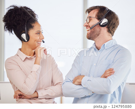 Call center, man and woman with headset have conversation, talking and discussion with smile, happy and in office. Customer service, client support and diversity with agents, speaking and laughing. 124795880