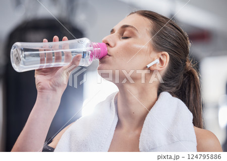 Gym, fitness and woman with earphones drinking water from bottle, cardio workout while listening to music on streaming radio. Sports, exercise and drink of water for healthy lifestyle while training. 124795886