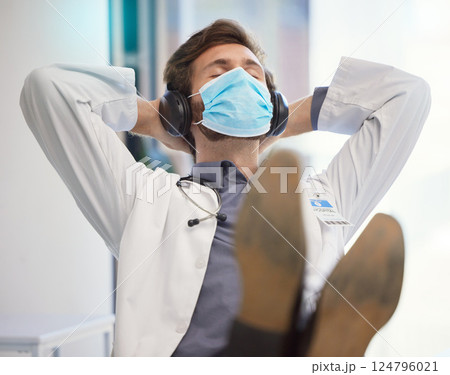 Doctor, covid face mask and relax in healthcare hospital with headphones to listen to music after finished task, job or pandemic. Medical worker man at work during covid 19 for safety and care Doctor, covid face mask and relax in healthcare hospital with headphones to listen to music after finished task, job or pandemic. Medical worker man at work during covid 19 for safety and care 124796021
