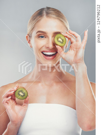 Happy studio portrait, woman with kiwi for skincare wellness, health and beauty by grey wall. Cosmetics model, girl with smile, fruit and self care for healthy facial, skin or vitamins by background 124796212