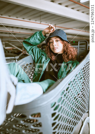 Fashion, parking lot and shopping cart portrait of woman student relaxing with edgy, trendy and carefree style at mall. City, young and urban fashionista girl in Mexico resting in customer trolley. 124796331