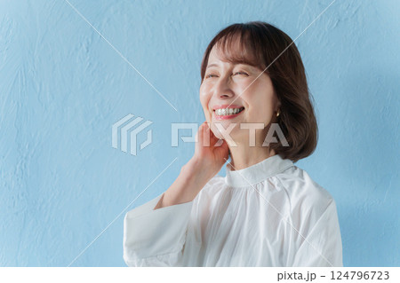 髪を触る中年女性（ブルーバック） 124796723