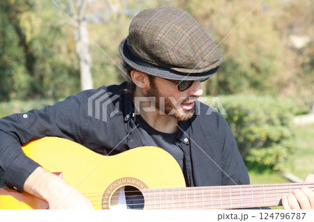 Male Street Artist Enjoys Playing Classical Guitar In A City Park 124796787