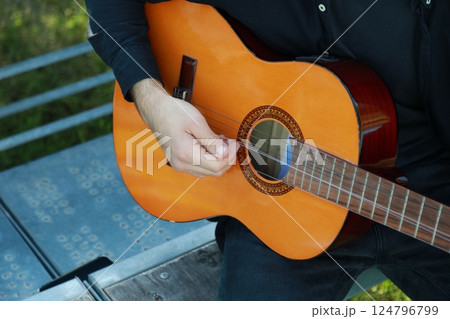 Man Tunes Guitar With Tuning Fork Outside 124796799